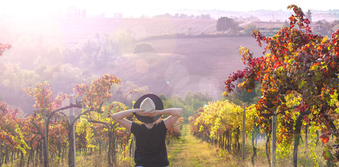 Girl in a hat at sunset. Nature Italy, hills and grape fields in the sunlight. Glare and sun rays in the frame. Free space for text. Copy space.