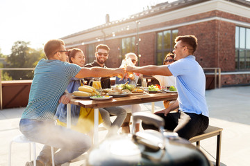 leisure and people concept - happy friends toasting drinks at barbecue party on rooftop in summer