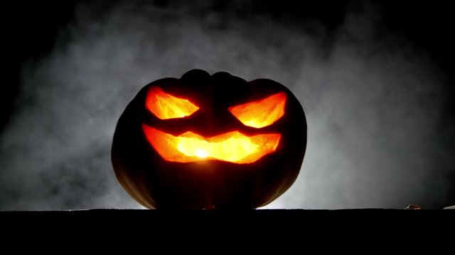 Scary pumpkin with burning eyes in the dark place with evil smoke background