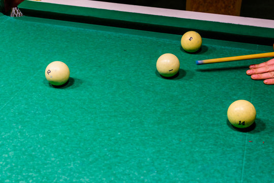 Player arm with the cue and balls on the green cloth. Russian billiard