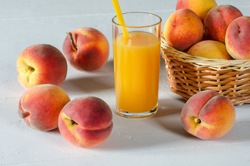 A glass with peach juice and ripe peaches.