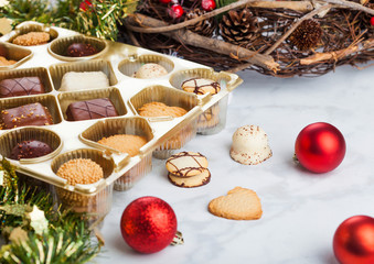 Luxury belgian christmas chocolate and biscuit cookies selection in box with christmas and new year holidays decoration on light background.