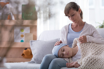 Worried mother and daughter with cancer taking rest at home