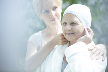 Caregiver helping sick elder woman with lung cancer