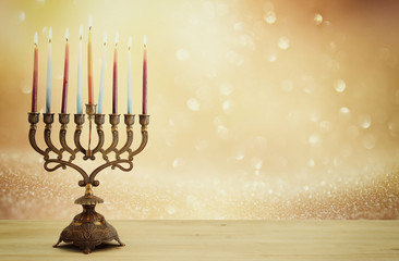 image of jewish holiday Hanukkah background with menorah (traditional candelabra) and candles over glitter shiny background.