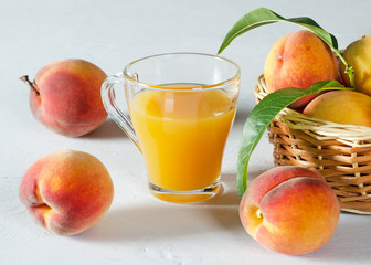 A glass with peach juice and ripe peaches.