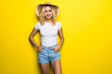 Happy young pretty woman straw hat posing in studio on yellow background
