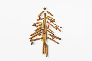 Christmas tree made of cinnamon sticks, cones, oranges and rosehip fruits. White background, flat lay, top view.
