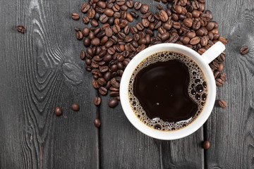 Cup of coffee and beans on wooden background