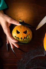 Foto op Plexiglas Photo of man's hands with pumpkin jack, knife sitting at wooden table © nuclear_lily