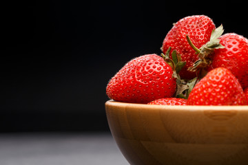 Photo close-up of ripe strawberry in wooden cup on black background