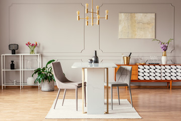 Industrial style, golden pendant light above an exceptional marble table in a trendy dining room...