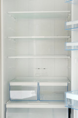 Fototapeta na wymiar Empty white shelves in refrigerator. Diet and hunger concept. Vertical image.