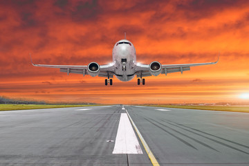 Fototapeta na wymiar Airplane flying arrives landing on a runway in the evening.