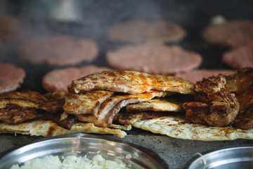 Variety of delicious meats being prepared on the grill in a street kitchen, selective focus