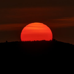 Sunrise over mountain peak, huge orange sun on top