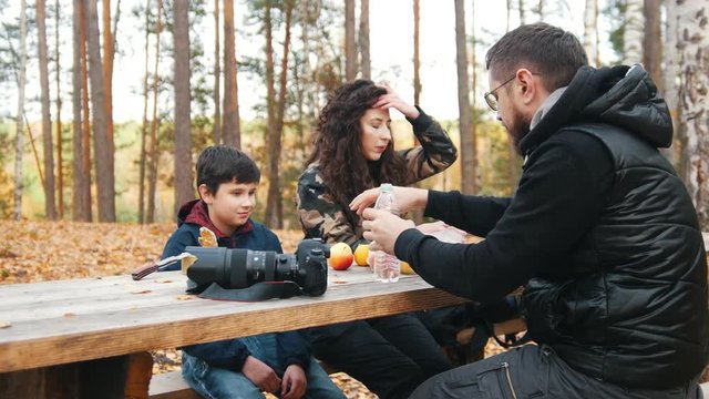 mom, dad and child sitting outdoors in the woods at the table