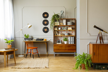 Vinyl records decorations on a gray wall with molding and wooden furniture in a retro home office...
