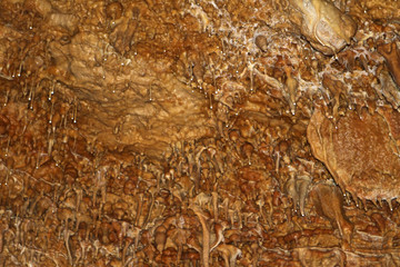 fantastic natural cave with brown walls and formations of stalactites and stalagmites within, natural texture image.