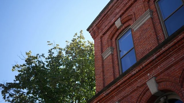 A, establishing shot of second story red brick building near tree 