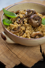 Bowl of pasta with cep boletus and champignons in a rustic wooden setting, vertical shot