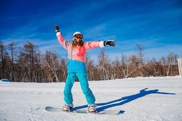 a young smiling woman rides on a snowboard