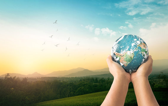 Earth Day concept: Human hands holding earth global over mountain sunrise background. Elements of this image furnished by NASA