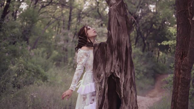 The good fairy lost the battle against evil, preparing for death. princess in the clutches of terrible monster and killer. forest nymph in white dress against the spirit of darkness. Creative colors