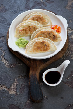 Fried potstickers with dipping sauces, vertical shot over brown stone background