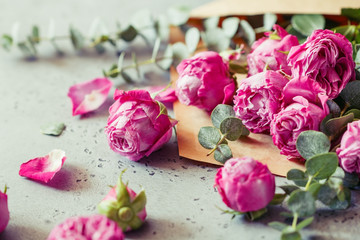 Pink roses in the envelope on a grey background. The concept of greetings and celebration. Copy space, soft focus.