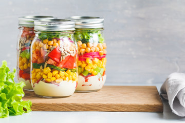 Three glass jars with layering various vegan salads for healthy lunch. Extrem close up. The concept of fitness and vegetarian food.