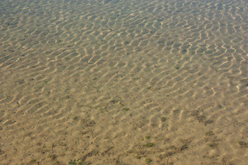 Sand at the bottom of the lake through the water.