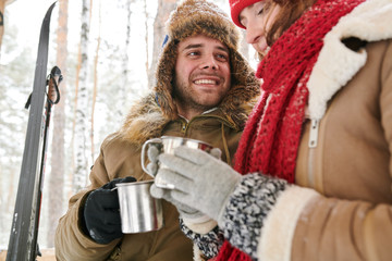 Waist up  portrait of loving young couple enjoying hot cocoa during date in beautiful winter...