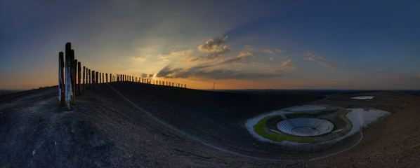 Game between sun and clouds in the evening behind a coal dump - obrazy, fototapety, plakaty
