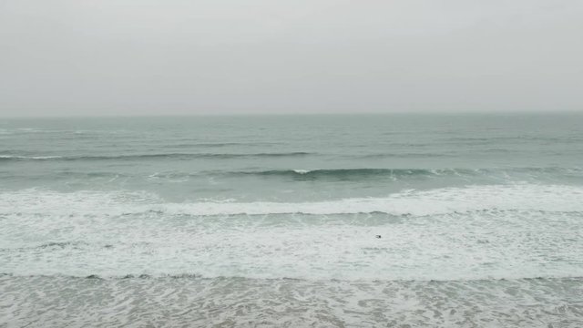 Surfers at Fistral Beach, Newquay, Cornwall on an overcast June day.