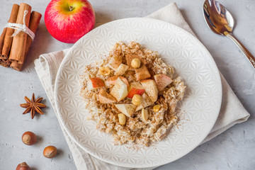 Oatmeal with fresh apples, nuts and cinnamon for Breakfast on the table, close-up, horizontal