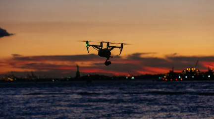 Fototapeta na wymiar Flying drone against colored by sunset, of New York at dark sky