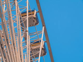 Low angle shot to a part of big wheel in playground park. Worm eye view Image of Ferris wheel. Uprise to look at a part of machine in sunny day. Take angle elevation to a beautiful blue sky.