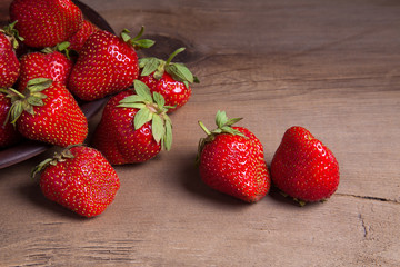 Strawberry fresh ripe sweet berry in clay plate on wooden background.