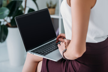 cropped view of businesswoman using laptop with blank screen