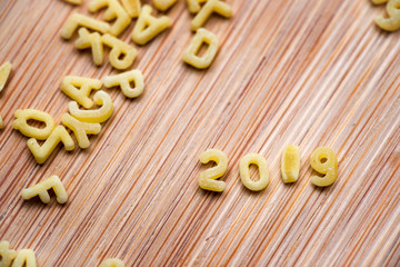 2019 written with alphabet pastas on wooden background
