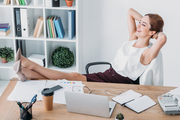 adult happy businesswoman sitting in chair with hand behind head at workplace