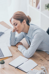 high angle view of overworked adult businesswoman sleeping at workplace in modern office