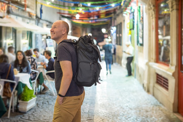 Tourist with big backpack sightseeing lively streets