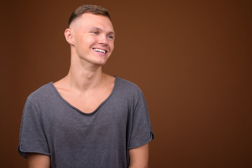 Obraz premium Young man wearing gray shirt against brown background