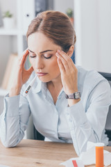 adult sick businesswoman with headache sitting at workplace with closed eyes
