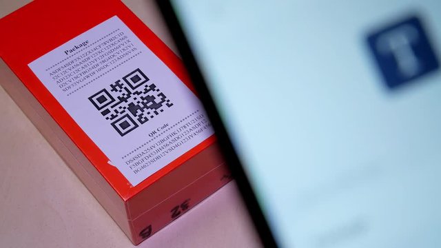 Smart phone scanning QR code in paper label on the orange package or parcel box