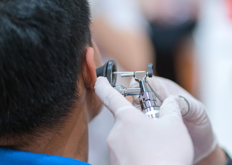 ENT physician checking patient's ear using otoscope with an instrument