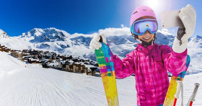 Teenager taking a selfie, girl taking a self portrait with mobile phone, sport skiing having fun on winter vacation.