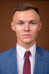 Young businessman wearing suit against brown background